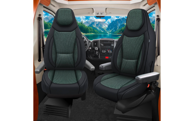 Zwei grün gepolsterte Vordersitze mit Armlehnen, Lenkrad und Armaturenbrett; große Frontscheibe zeigt See, Berge und blauen Himmel