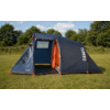 Tente de camping bleu foncé avec bordure orange et entrée avant ouverte, posée sur de l'herbe avec des arbres et un ciel partiellement nuageux en arrière‑plan, inscription 'TAMBU' visible sur le côté