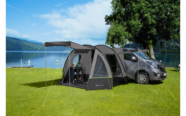 Car with attached tent on a green lawn next to a lake