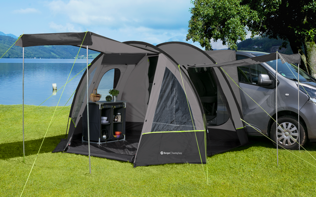 Voiture avec tente attachée sur une pelouse verte à côté d'un lac