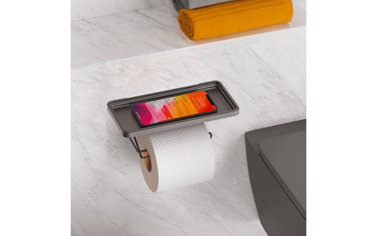 Smartphone in Halterung über einer Toilettenpapierrolle auf grauer Badezimmeroberfläche