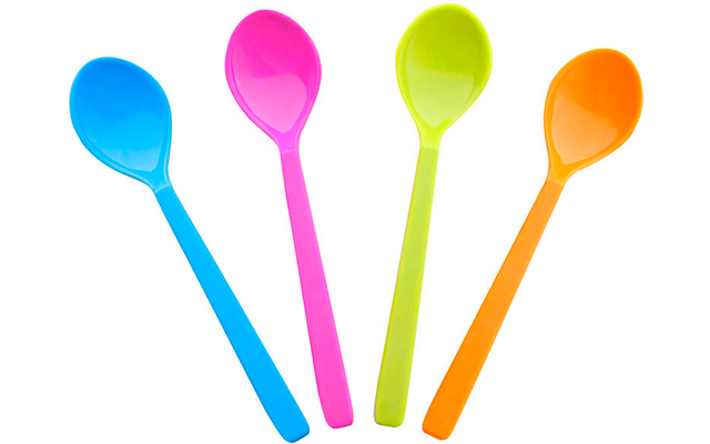 Vier bunte Löffel in Blau, Rosa, Grün und Orange, fächerförmig auf weißem Hintergrund