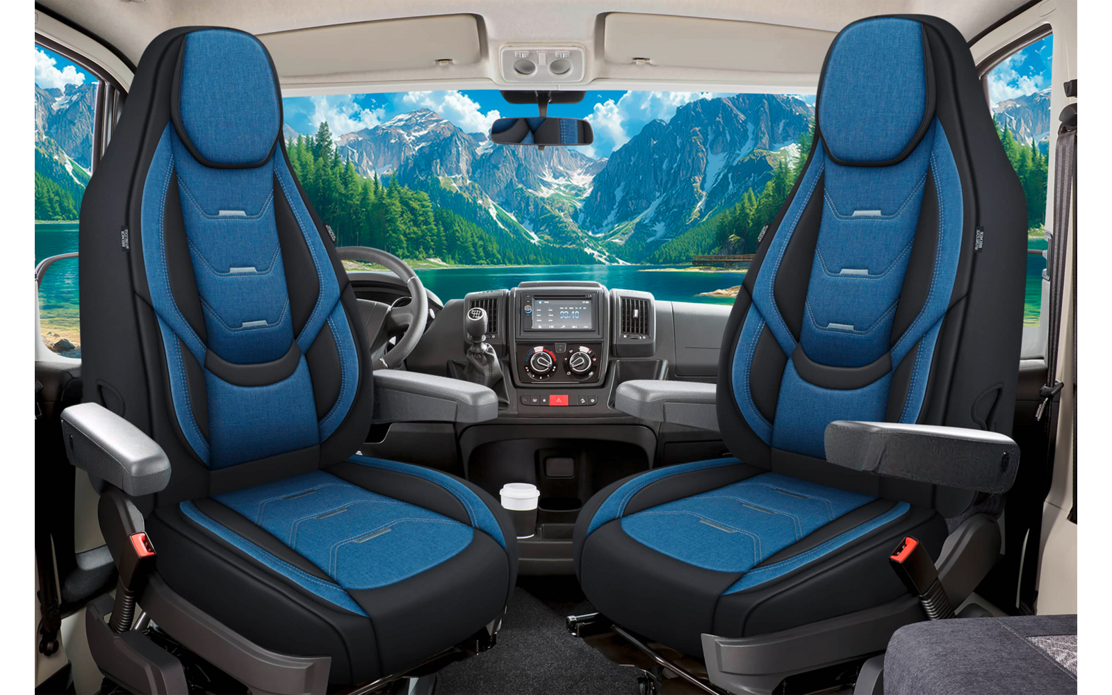 Zwei blaue Vordersitze mit Armlehnen, Armaturenbrett und Lenkrad, große Windschutzscheibe zeigt Bergsee