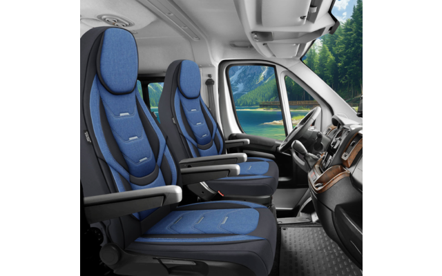 Innenraum eines Fahrzeugs mit zwei blauen Vordersitzen, Armlehnen, Sicherheitsgurten, Lenkrad, Armaturenbrett und Blick durch das Fenster auf einen See und bewaldete Berge