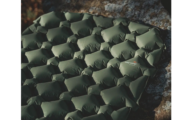 Grüner, gepolsterter Outdoor-Sitzsack auf grauem Boden neben Steinmauer