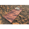 Sac de couchage rectangulaire orange avec doublure intérieure blanche visible, posé sur du sable ; aucune personne visible