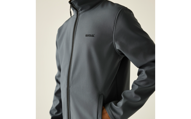 Teilansicht eines Oberkörpers in grauer Jacke mit durchgehendem Reißverschluss und hohem Kragen, Hand in seitlicher Tasche, kleines schwarzes Logo auf der Brust