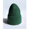 Gorro de punto verde acanalado con puño vuelto y pequeña placa metálica sobre fondo blanco