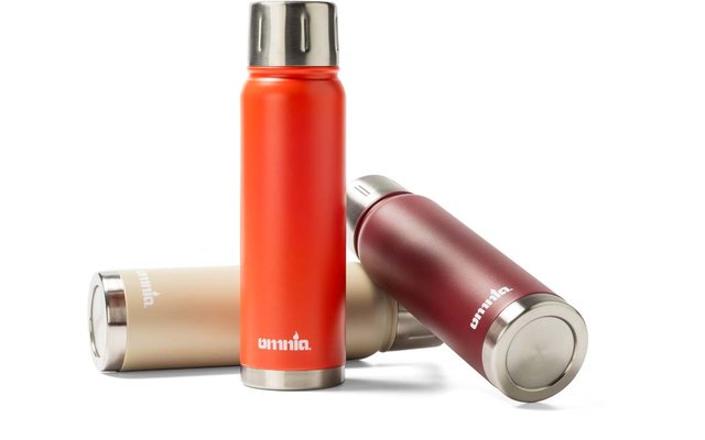 Drie metalen drinkflessen: één oranje fles rechtop vooraan, een goud-beige en een donkerrode fles liggend achteraan, allemaal met zilverkleurige schroefdoppen