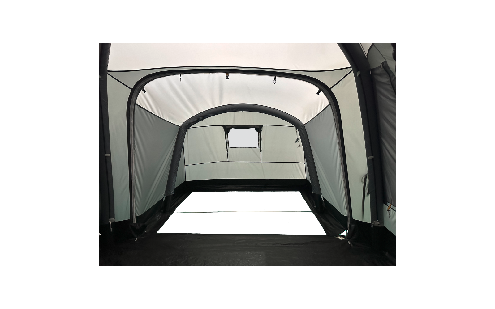 Innenraum eines hellgrauen Zelts mit gebogenen Stangen, rechteckigem Fenster an der Stirnseite und schwarzem Boden
