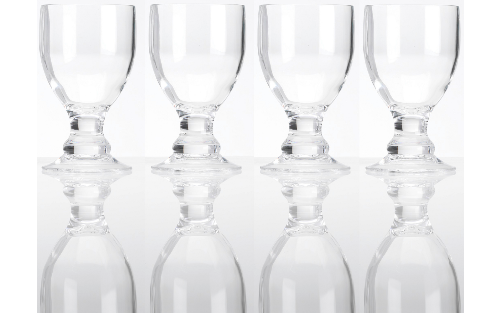 Vier lege, heldere drinkglazen naast elkaar op een reflecterend oppervlak