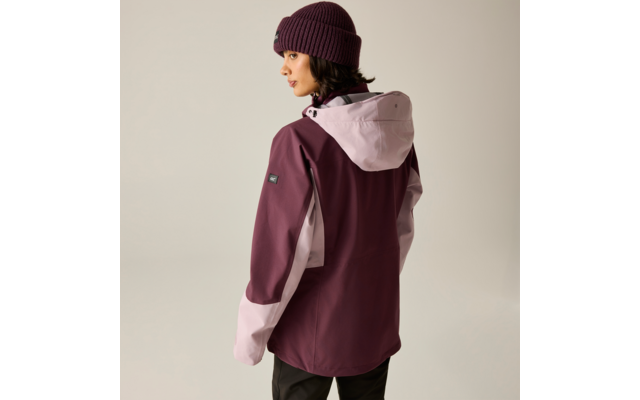 Person von hinten/seitlich, trägt zweifarbige plum- und rosa Kapuzenjacke, gestrickte Mütze, schwarze Hose, heller neutraler Hintergrund