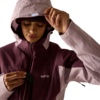 Person mit zweifarbiger Kapuzenjacke (hellrosa/dunkelviolett), Kapuze aufgesetzt, eine Hand hält die Krempe, andere Hand an Reißverschluss, weißes Logo auf der Brust