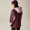 Person von hinten/seitlich, trägt zweifarbige plum- und rosa Kapuzenjacke, gestrickte Mütze, schwarze Hose, heller neutraler Hintergrund