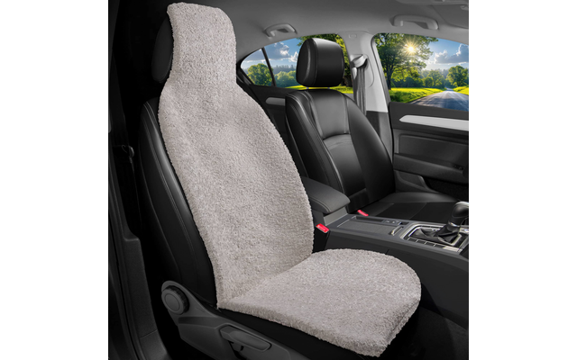 Innenraum eines Autos mit schwarzen Ledersitzen; linke Vordersitzfläche bedeckt von hellgrauem, flauschigem Sitzbezug; Mittelkonsole mit Schalthebel; durch die Fenster sichtbar: Straße, Bäume und Sonne