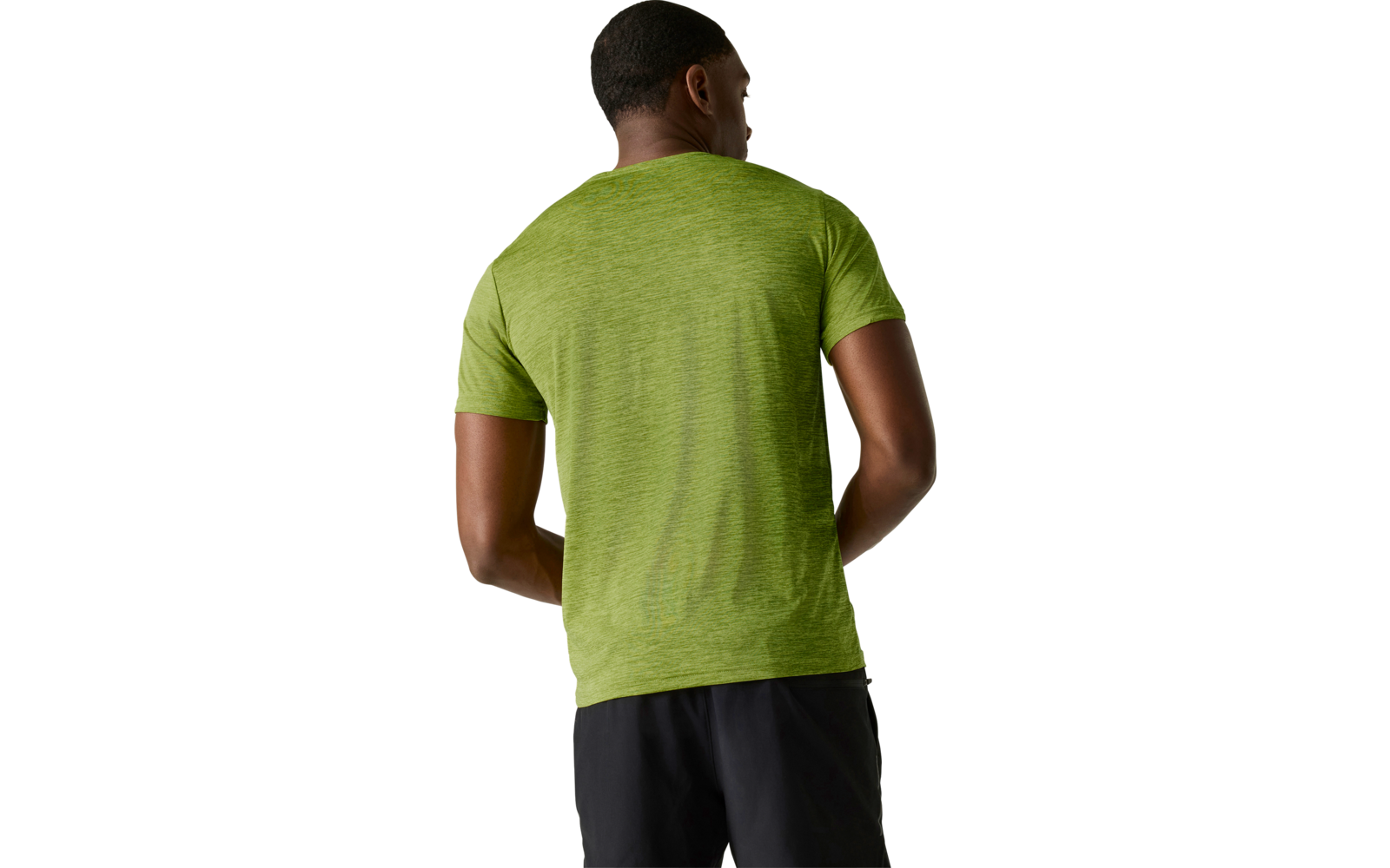 Person von hinten, trägt grünes kurzärmeliges T‑Shirt und schwarze Shorts vor hellem, neutralem Hintergrund