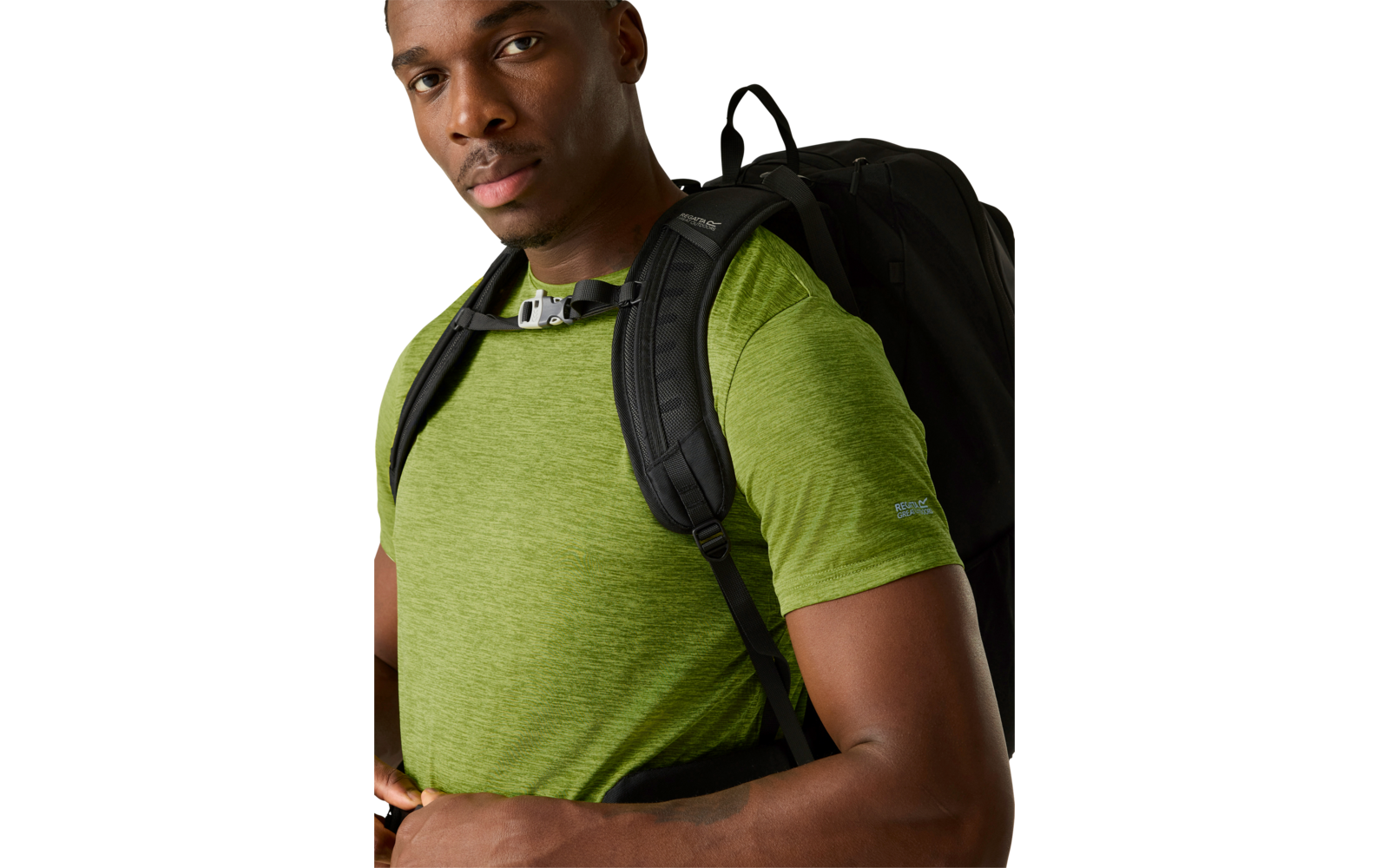 Mann mit grünem T-Shirt und schwarzem Rucksack, Oberkörper sichtbar, Hände an den Rucksackriemen