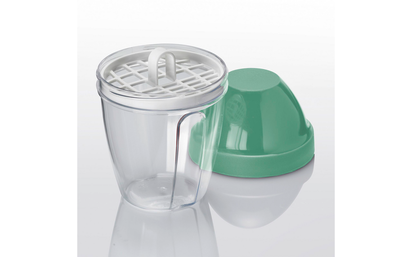 Gobelet en plastique transparent avec insert à grille blanc amovible muni d'une poignée en boucle, à côté d'un couvercle plastique vert en forme de dôme sur une surface réfléchissante