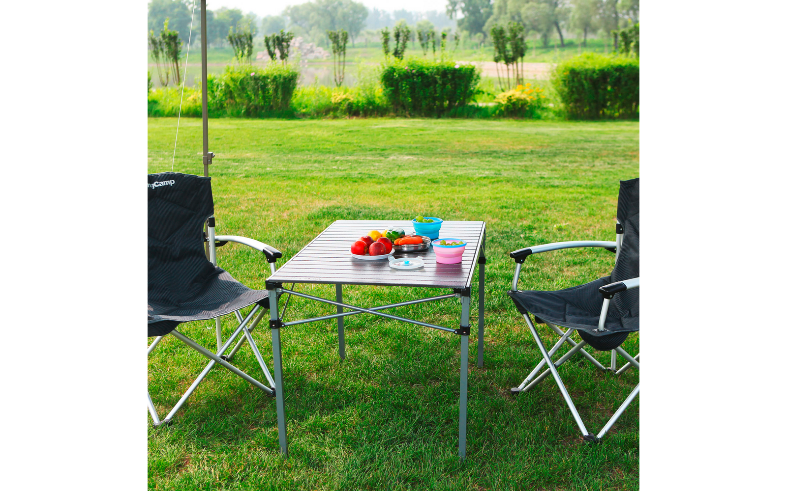 Deux chaises de camping et une table pliante avec des voitures jouets en plein air sur l'herbe