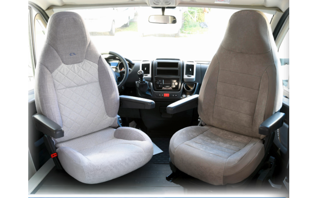 Two driver and passenger seats in a vehicle, light gray and beige, with armrests and steering wheel in the background