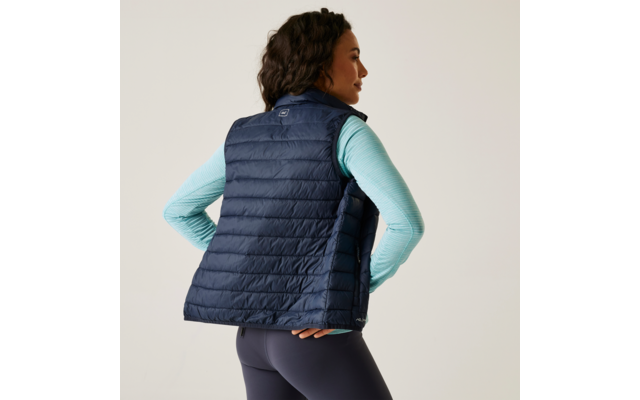 Vrouw van achteren met donkerblauw doorgestikt vest en lichtgekleurde trui