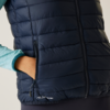 Persoon draagt een donkerblauwe gewatteerde bodywarmer, hand in de zak