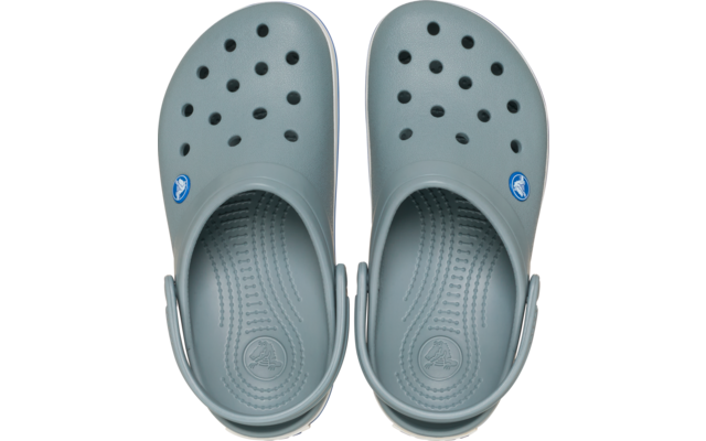 Paar lichtgrijze rubberen klompen van bovenaf, met meerdere ventilatiegaatjes, omgeklapte hielriemen en een rond logo aan de buitenkant