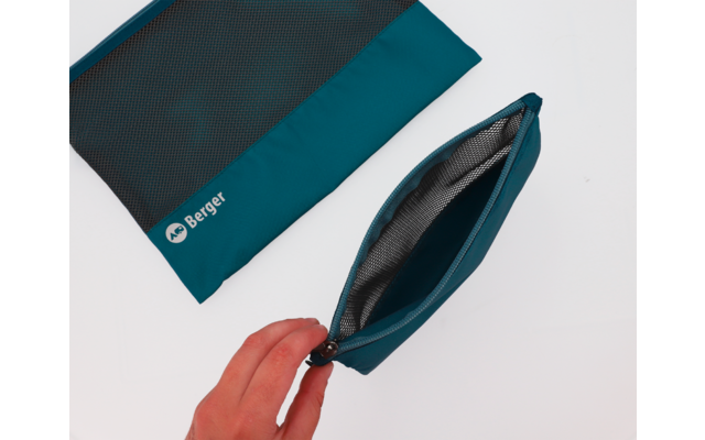 Hand öffnet eine kleine blaue Tasche auf einem weißen Untergrund