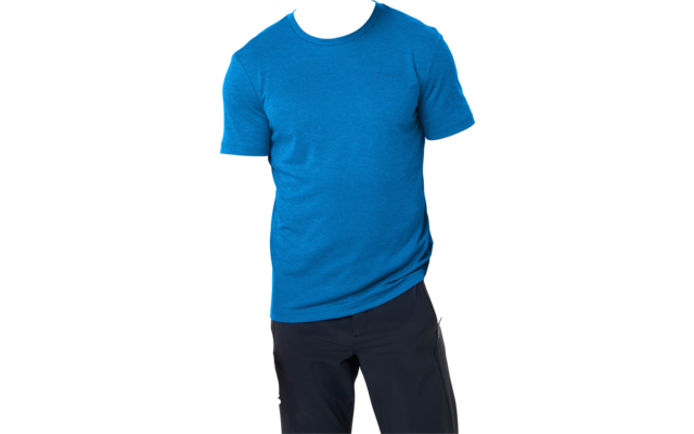 Jonge man met kort haar, draagt een blauw T‑shirt met korte mouwen en een donkere broek, staat voor een witte achtergrond, één hand in de zak