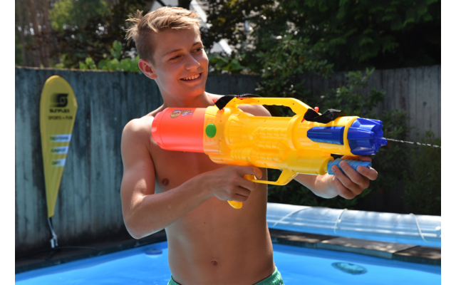 Junge mit Schwimmbrille hält eine gelbe Wasserpistole am Pool