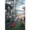 Person mit Fahrradhelm befestigt ein E‑Bike an einem Heckfahrradträger neben einem See