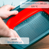 Deux mains tiennent une passoire rectangulaire à bord rouge et fond turquoise perforé ; inscriptions visibles : 'HITZEBESTÄNDIG BIS ZU 120 °C' et 'MAßE 39 x 26 x 12 cm'