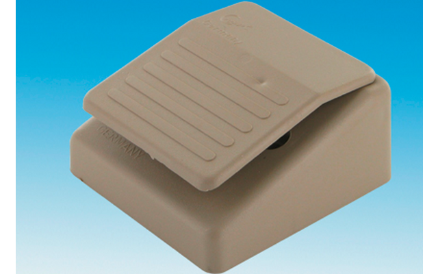 Beige rectangular foot pedal with a ridged top surface on a blue-to-white gradient background