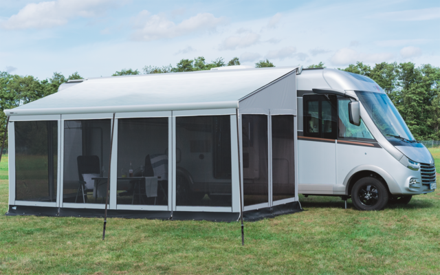 Camper met aangebouwde witte luifel op groen gras