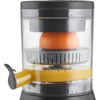 Demi-orange sous un presse-agrumes dans un récipient transparent, jus recueilli en dessous et bec verseur avec levier
