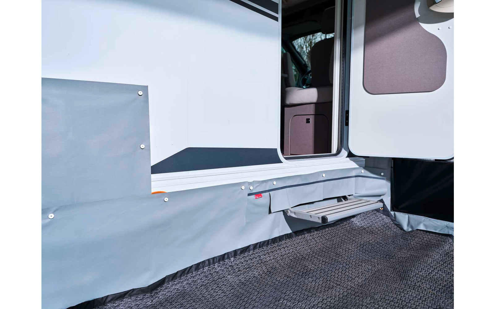 Porte de véhicule ouverte avec marche déployée, couverture latérale grise et tapis de sol texturé