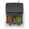 Zwart keukenapparaat met twee uitgetrokken vakken; links licht gebruinde kleine aardappelen, rechts groene asperges met bruining; digitaal display boven en netsnoer zichtbaar