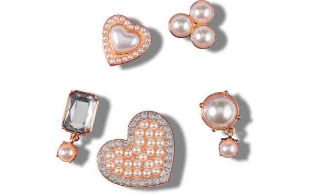 Cinco piezas en oro rosado: dos elementos en forma de corazón con pequeñas perlas y piedras claras; un grupo de tres perlas redondas; una gema clara rectangular facetada con una pequeña perla colgante; una perla redonda grande con una perla colgante pequeña