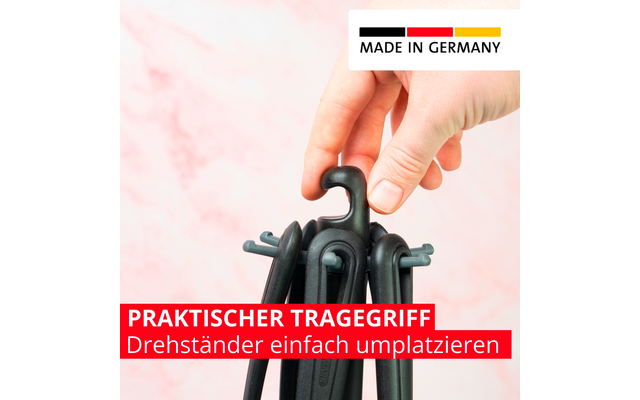 Main tenant une poignée noire en plastique avec plusieurs crochets noirs regroupés devant un fond rose marbré; en haut à droite autocollant 'MADE IN GERMANY' avec bandes noire, rouge et jaune; en bas bandeau rouge avec texte blanc 'PRAKTISCHER TRAGEGRIFF Drehständer einfach umplatzieren'