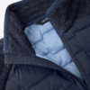 Nahaufnahme einer dunkelblauen gestepp­ten Jacke mit hellblauer Innenfütterung, Reißverschluss und strukturiertem Kragen
