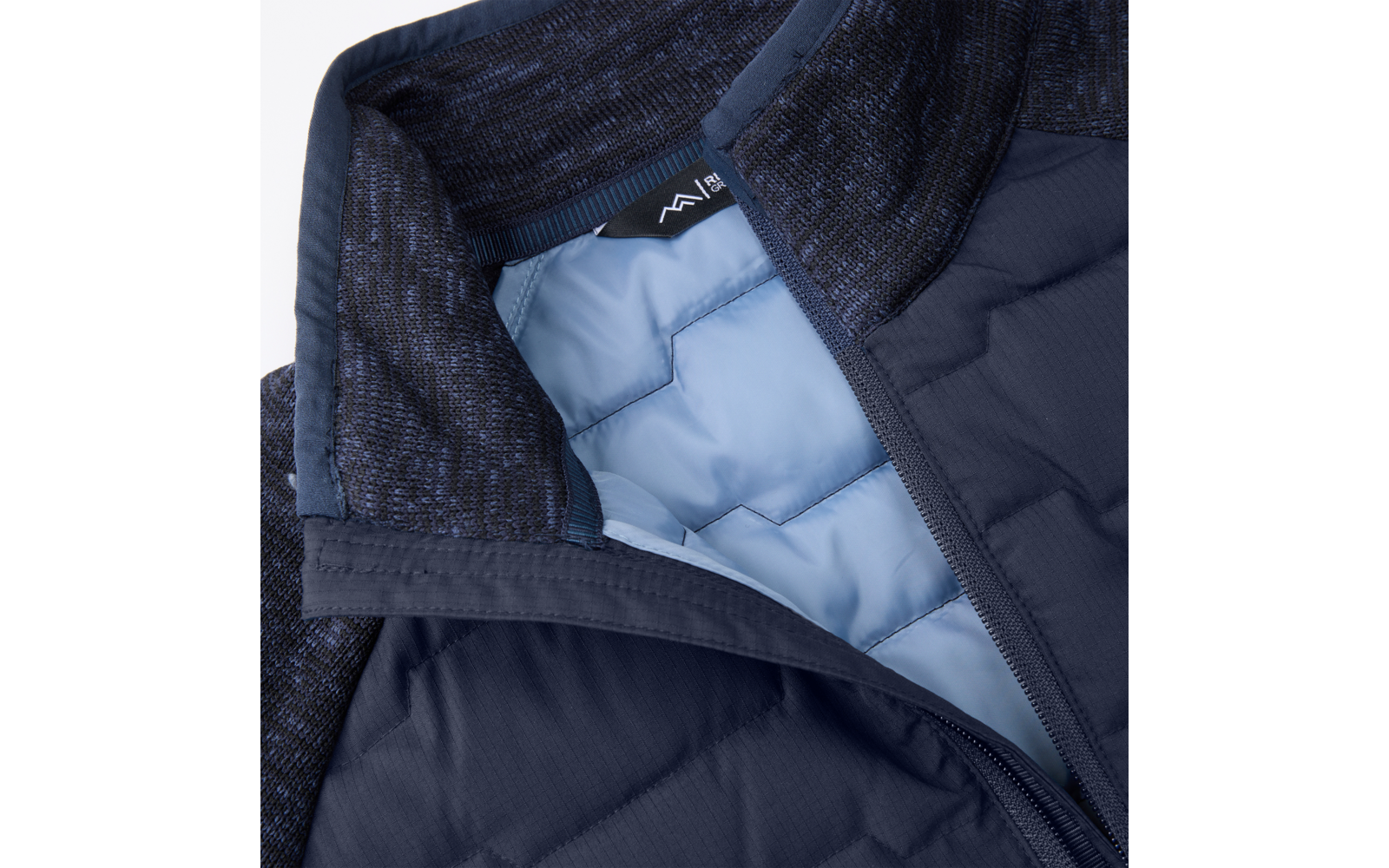 Nahaufnahme einer dunkelblauen gestepp­ten Jacke mit hellblauer Innenfütterung, Reißverschluss und strukturiertem Kragen