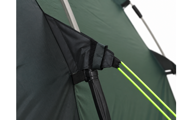 Close-up van groen tentdoek met een zwarte klittenbandriem, een zilverkleurige stokboog en twee neon-groene scheerlijnen bevestigd aan een zwart kunststof onderdeel