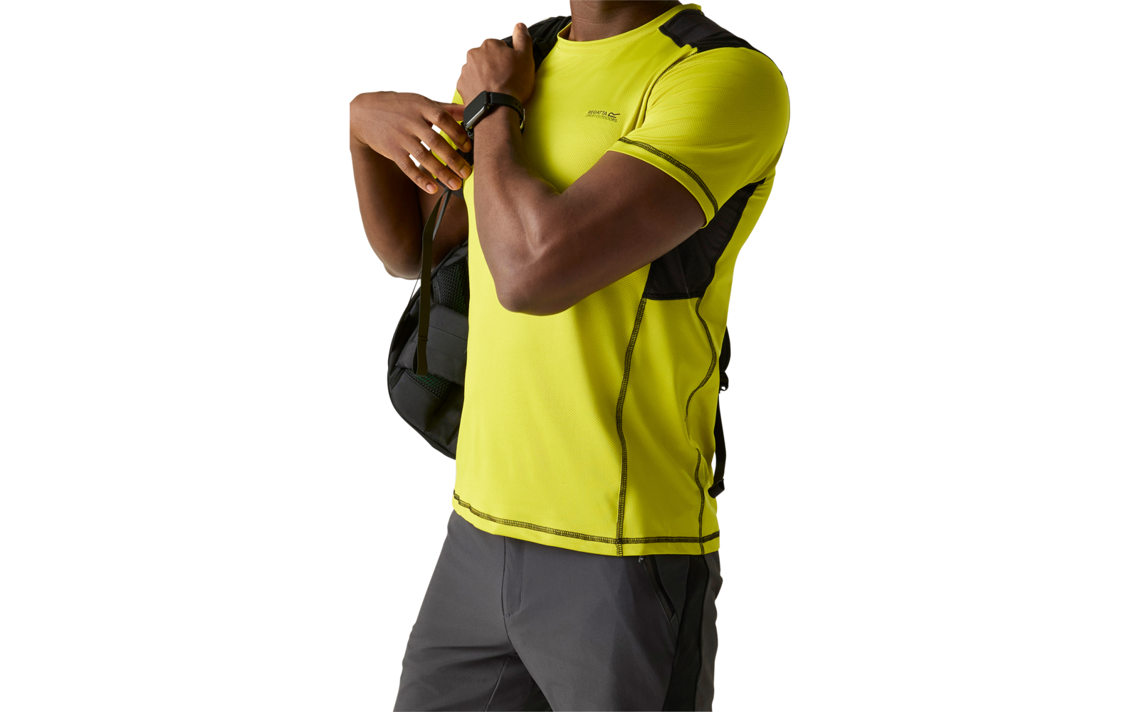 Oberkörper einer Person in neon-gelbem kurzärmligem T-Shirt mit schwarzem Rucksackriemen, sichtbare Hand mit Smartwatch, graue Shorts