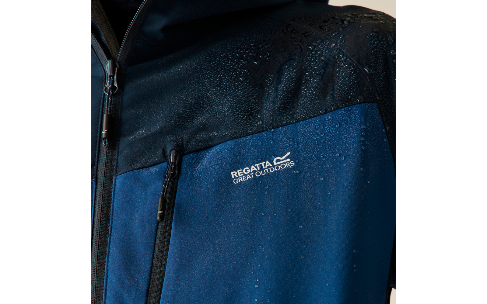 Nahaufnahme des oberen Teils einer blau-schwarzen Jacke mit Wasserperlen, zwei Reißverschlüssen und dem Schriftzug 'Regatta Great Outdoors'