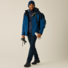 Person in blauer Jacke und Mütze, mit Rucksack, hält Stöcke und eine Metall-Trinkflasche, dunkle Hose und Wanderstiefel, heller einfarbiger Hintergrund
