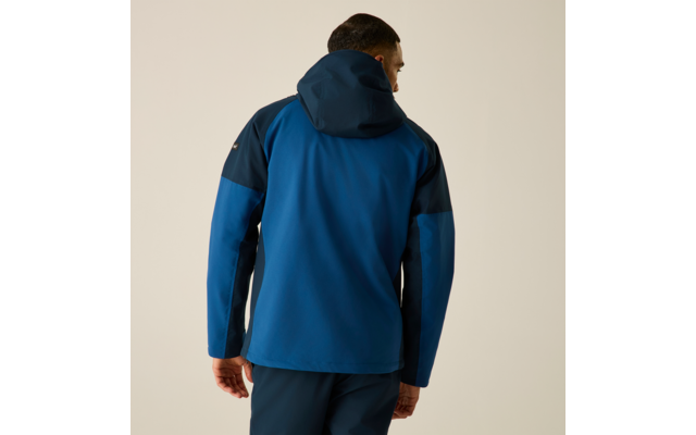 Person von hinten, trägt blaue Kapuzenjacke und dunkle Hose, Hände an den Seiten, heller einfarbiger Hintergrund