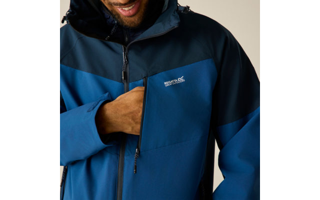 Oberkörper einer Person in blau-dunkelblauer Outdoorjacke, Hand in Reißverschluss-Brusttasche, weißes Logo 'Regatta', unterer Teil des Gesichts sichtbar