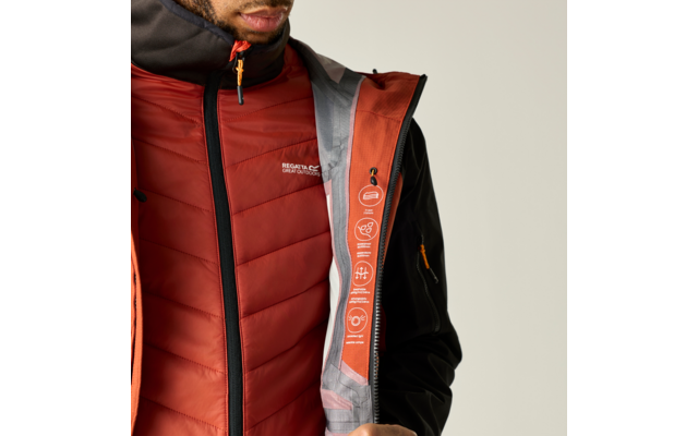 Oberkörper von Kinn bis Hüfte, trägt rote gesteppte Weste und offene orange Jacke mit grauem Futter und aufgedruckten Symbolen am Innenreißverschluss