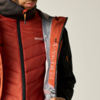 Oberkörper von Kinn bis Hüfte, trägt rote gesteppte Weste und offene orange Jacke mit grauem Futter und aufgedruckten Symbolen am Innenreißverschluss