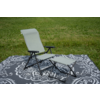Fauteuil-longue pliant vert clair avec structure métallique noire et repose-pieds assorti sur un tapis gris foncé à motifs sur l'herbe